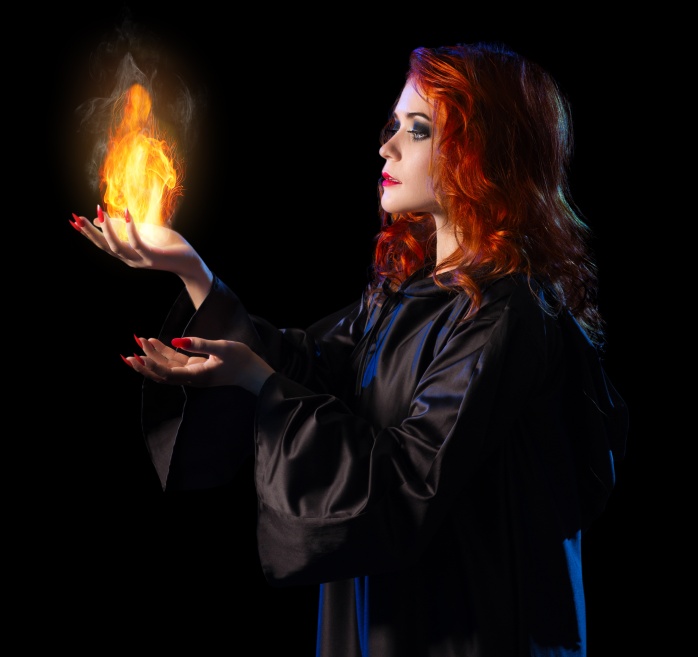 Young witch with flame isolated